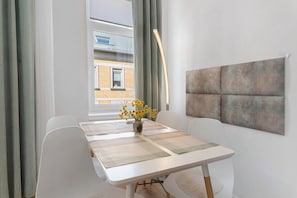 A dining area with a table, chairs, a vase with flowers, and a wall-mounted artwork. - Apartment 'Baba' with Wi-Fi in Gera (Gera)