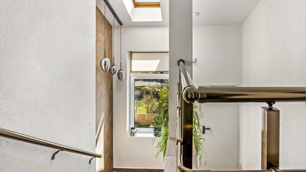 A modern interior with a skylight, a staircase, and a view of a garden.