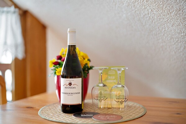 A bottle of wine, two wine glasses, and a coaster on a table.