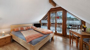 Une chambre à coucher avec un lit en bois, une table de chevet, un bureau avec une chaise et une grande fenêtre donnant sur un beau paysage.