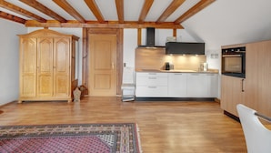 A kitchen with wooden beams, a large cabinet, a microwave, and a stove.