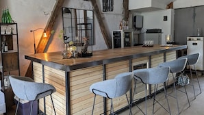 A modern kitchen with a wooden bar area, bar stools, and a refrigerator.