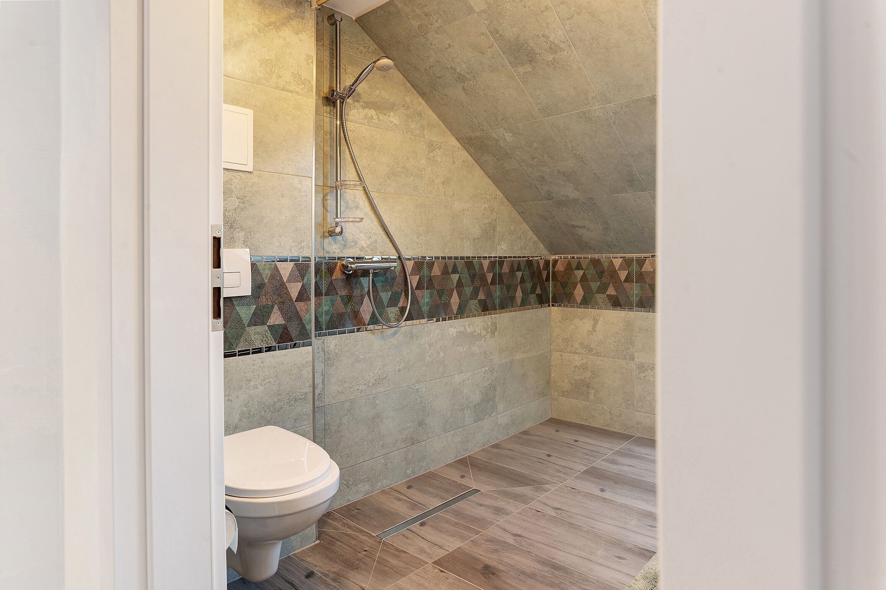 Une salle de bain avec une douche, des toilettes et un mur carrelé.
