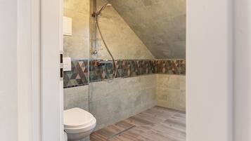 Une salle de bain avec une douche, des toilettes et un mur carrelé.