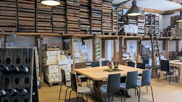Un intérieur rustique avec des caisses en bois, une table en bois entourée de chaises et des bouteilles de vin.