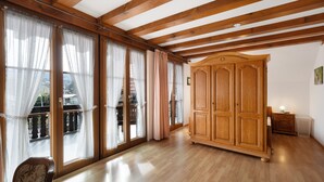 A room with wooden beams, large windows with sheer curtains, a wooden wardrobe, and a radiator. - Room 'Müller Thurgau' with Private Balcony, Wi-Fi / Including Breakfast (Endingen am Kaiserstuhl)