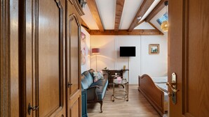 A room with wooden floors, a sofa, a bed, a TV, and a cabinet.