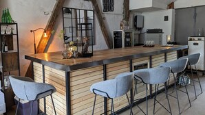 A modern kitchen with a wooden bar area, bar stools, and a refrigerator.
