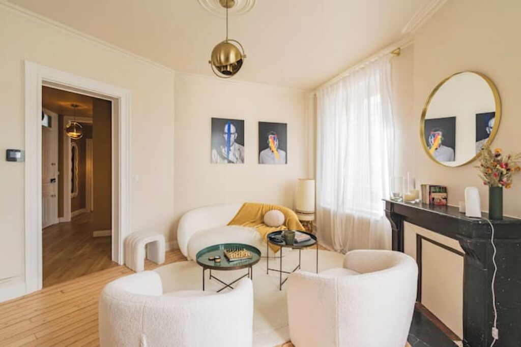 A modern living room with a fireplace, a chandelier, and artwork on the walls.