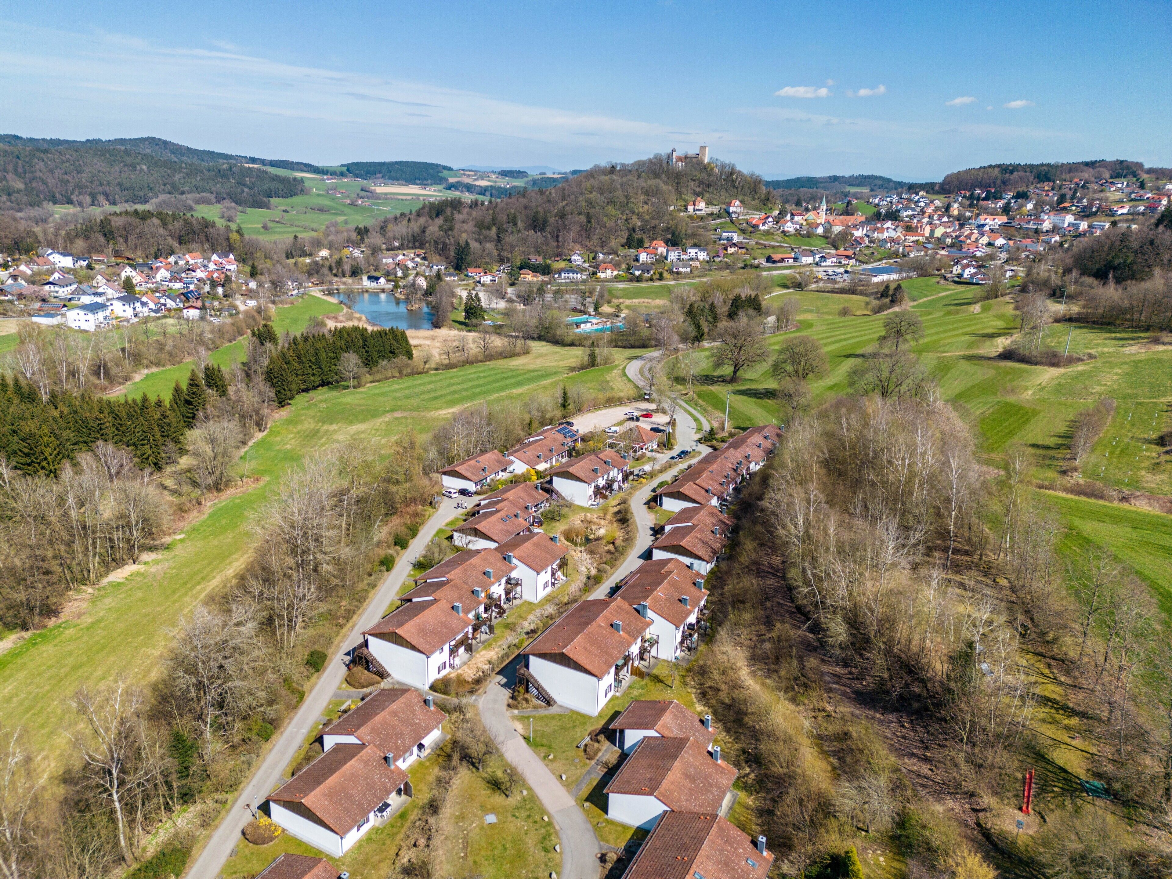 Vista aérea de una zona residencial con casas, una carretera y un castillo distante en una colina.