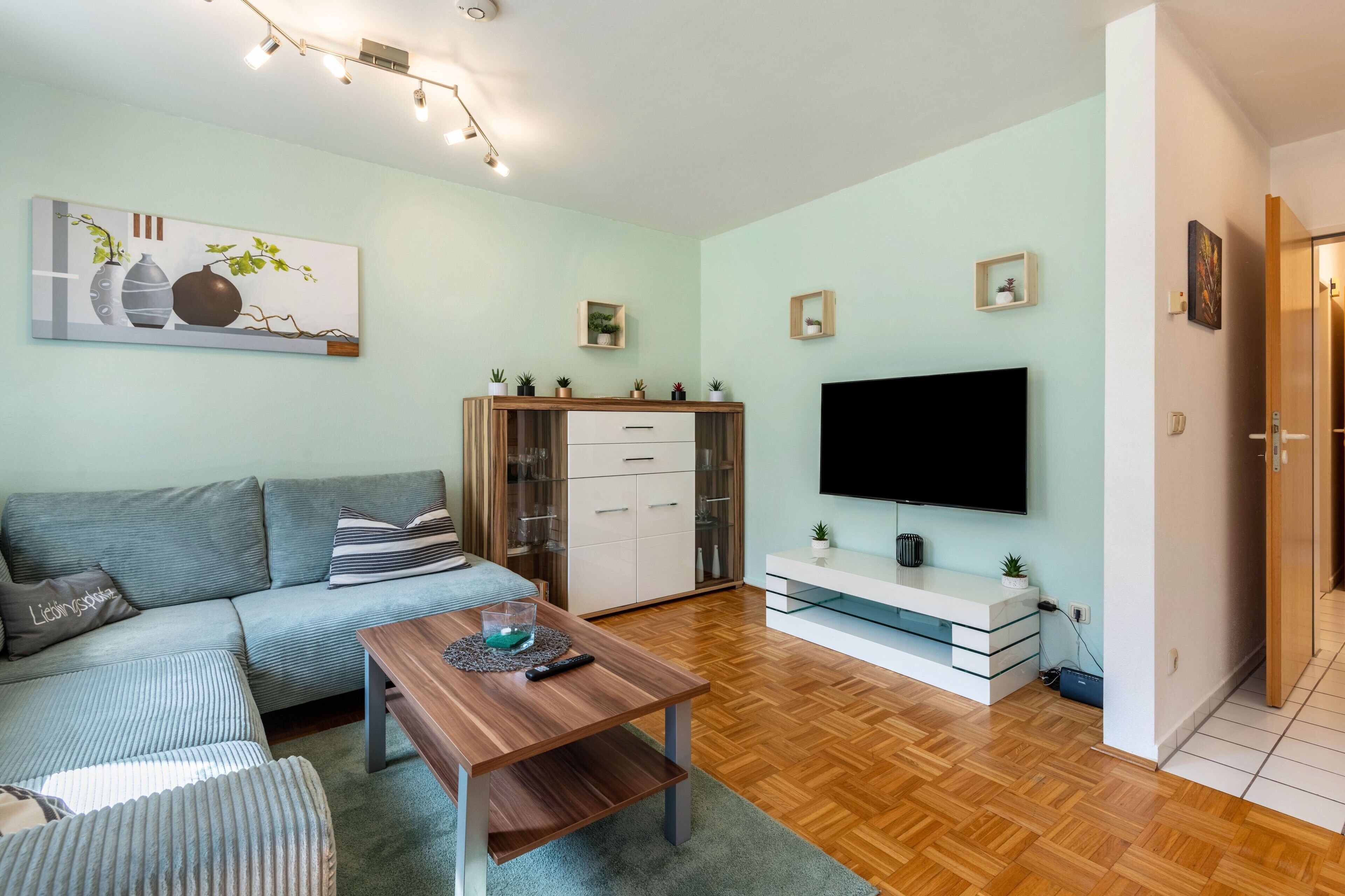 Una sala de estar moderna con sofá, mesa de centro, televisor y mueble.