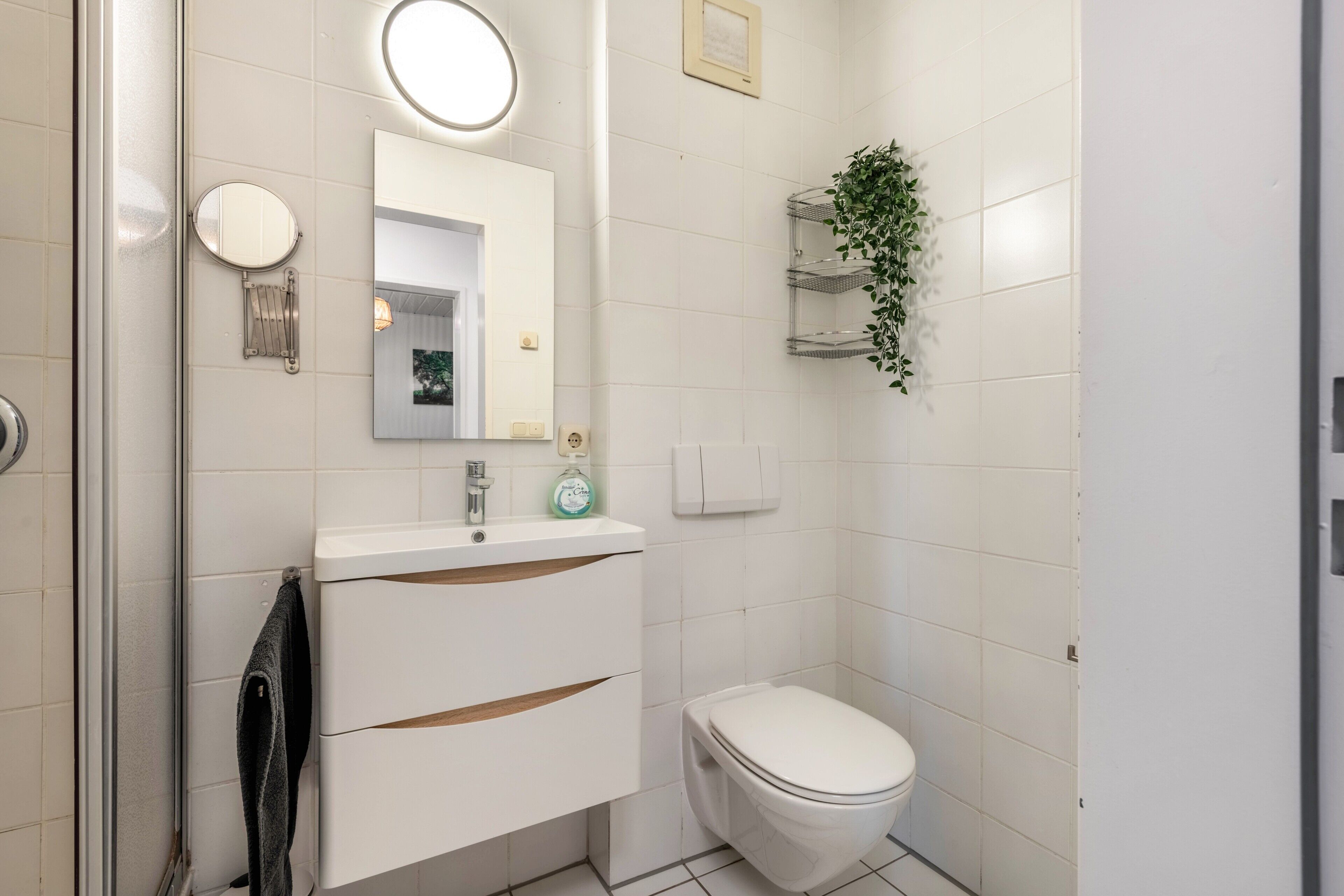 A bathroom with a white sink, mirror, and toilet.