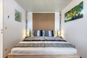 A bedroom with a bed, a wooden headboard, a wall-mounted plant, and a framed picture. - Holiday Apartment 'Fewo mit Terrasse - Dogs Welcome' with Mountain View, Terrace and Wi-Fi (Falkenstein)