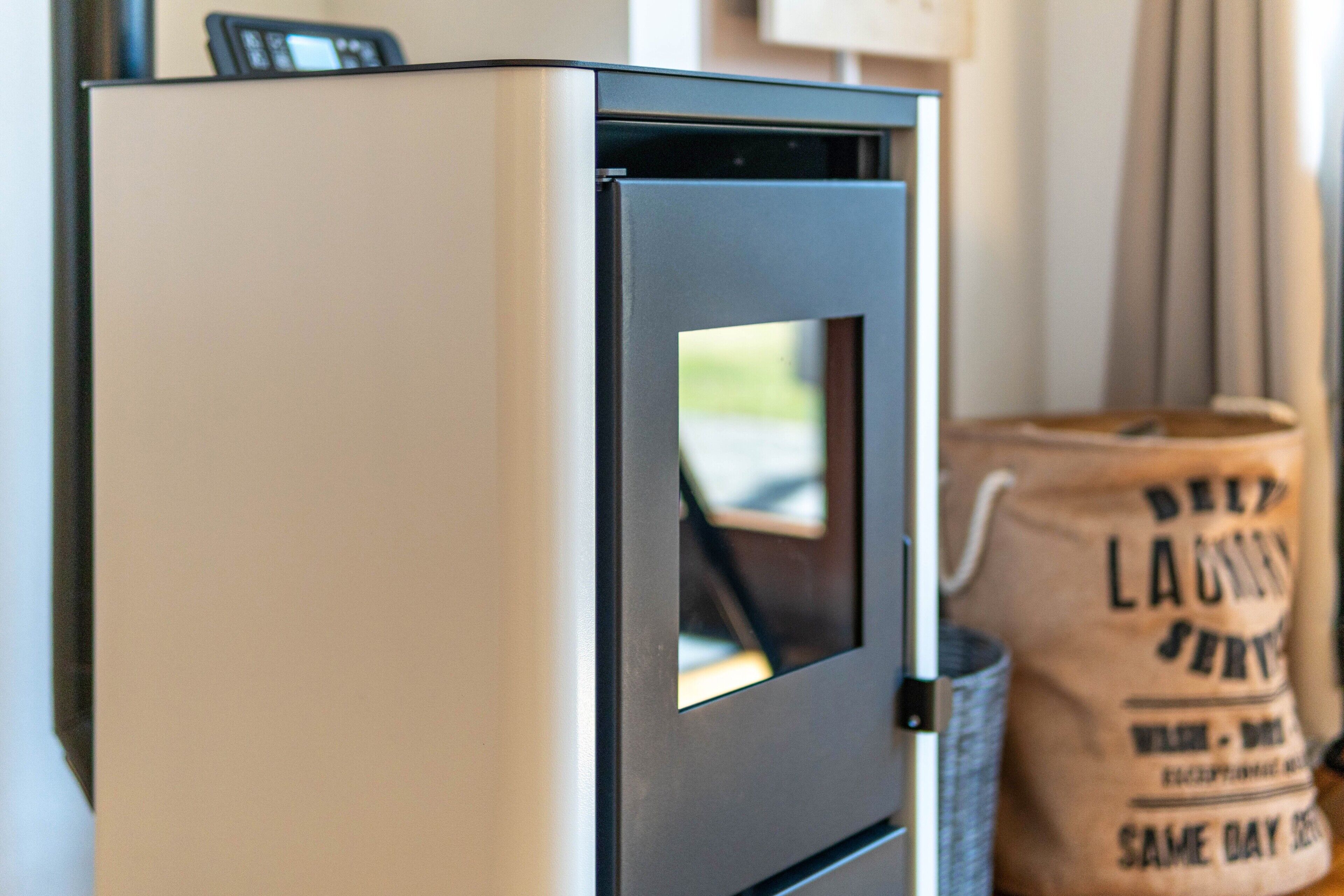A white refrigerator with a black handle, a small window, and a bag of laundry in the background.