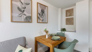 Ein Essbereich mit einem Holztisch, grünen Stühlen und gerahmten Kunstwerken an den Wänden.