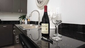 Uma cozinha com uma garrafa de vinho, uma taça de vinho e um saca-rolhas no balcão.