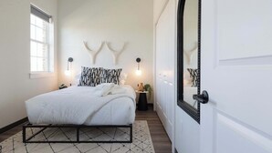 Un dormitorio con cama, ventana, puerta y elementos decorativos en la pared.