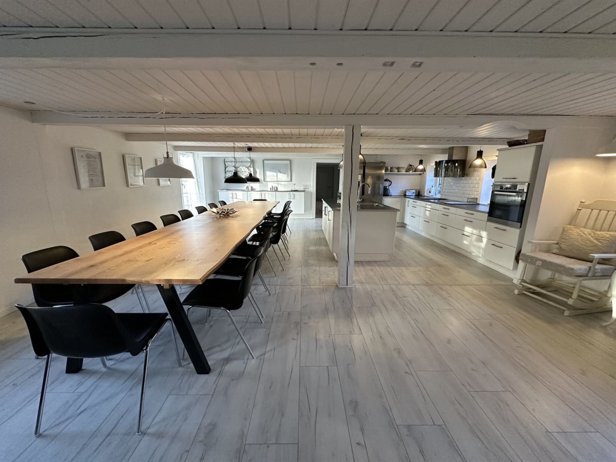 Eine moderne Küche mit weißen Schränken, einem Holztisch und schwarzen Stühlen.