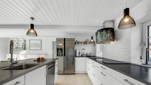 A modern kitchen with white cabinetry, stainless steel appliances, and pendant lighting.
