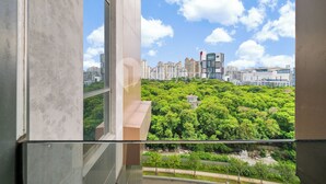 A view from a balcony overlooking a cityscape with high-rise buildings and a park.