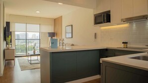 A modern kitchen with a central island, built-in appliances, and a view of the city through large windows. - w* | Astonishing 1BR w/ Great Deco in San Isidro (Lima)