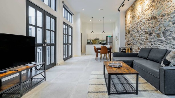 Un salón amplio con un televisor grande, un sofá, una mesa de centro y una pared decorativa de piedra.