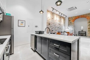 A modern kitchen with a central island, stainless steel appliances, and a stone accent wall. - w* | Roomy 1BR in Plaza Catedral (Panamá)