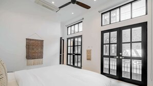 Un dormitorio con una cama grande, varias ventanas y un ventilador de techo.