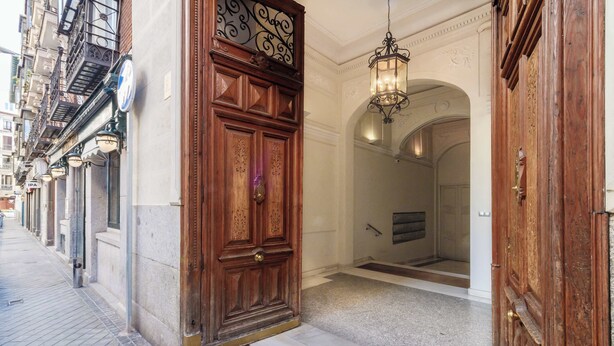 L’entrée d’un hôtel, avec une grande porte en bois, une enseigne au-dessus et un luminaire placé au-dessus de la porte.