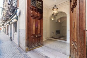 A hotel entrance with a large wooden door, a sign above it, and a light fixture above the door. - w* | Remarkable 1BR with lovely decor in Justicia (Madrid)