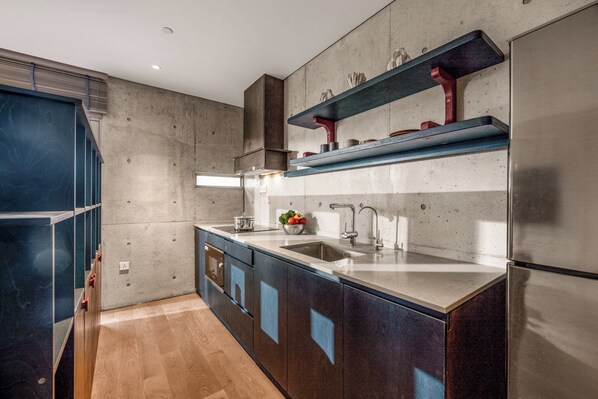 A modern kitchen with a large island, stainless steel appliances, and built-in shelving.