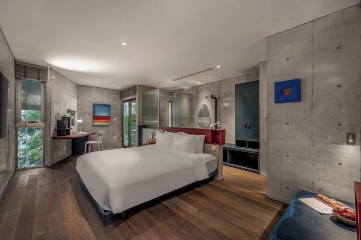 A modern bedroom with a large bed, a desk, and a vanity.