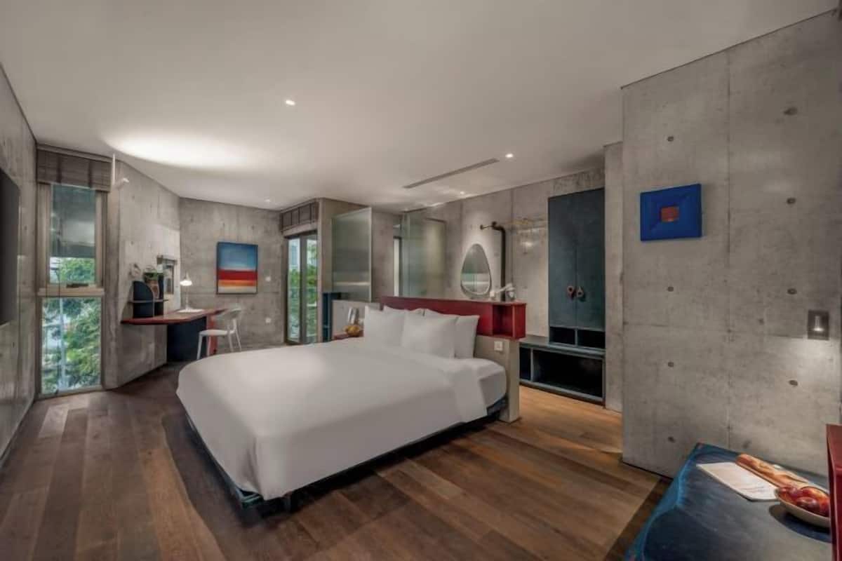 A modern bedroom with a large bed, a desk, and a vanity.