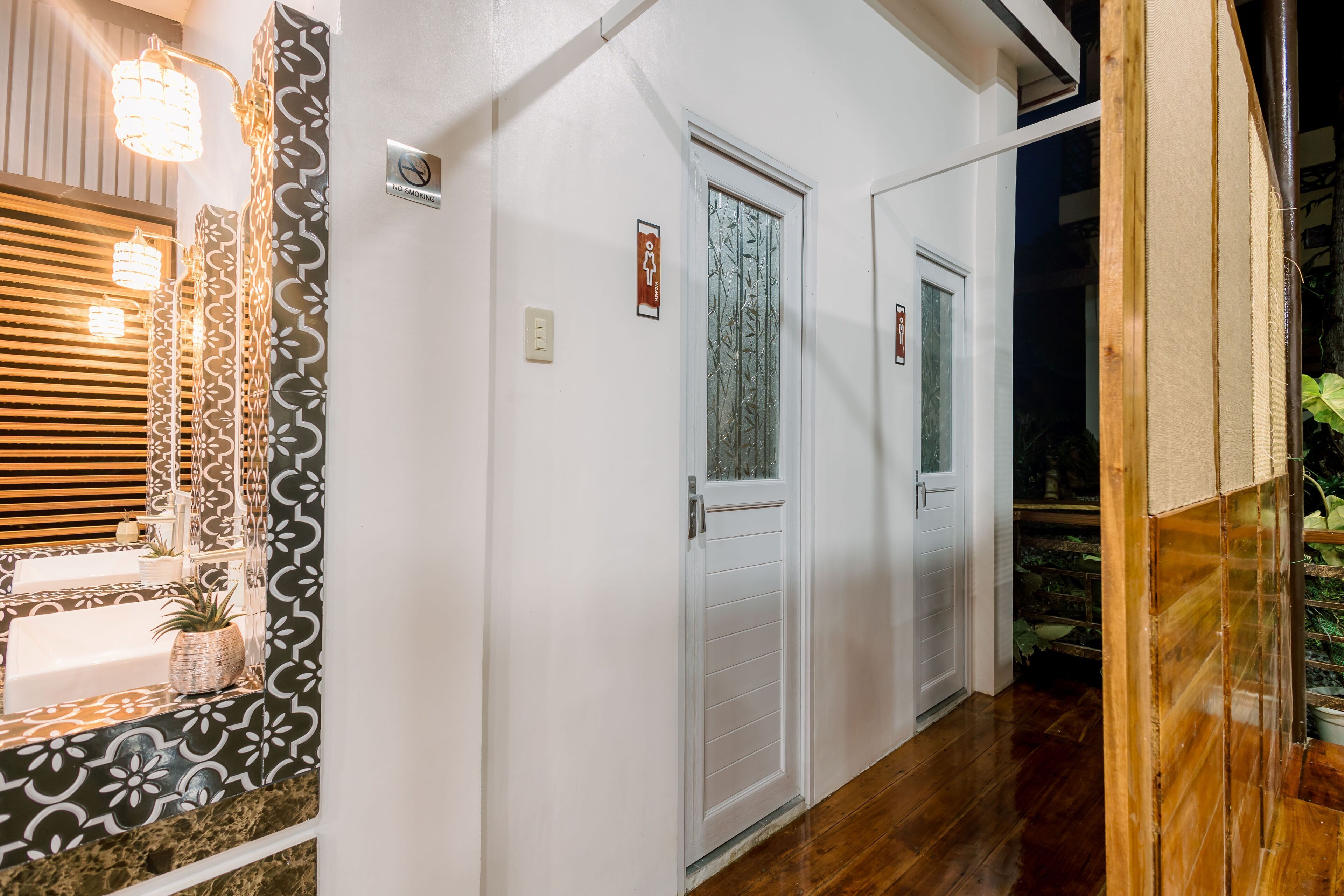 A hallway with a white wall, a wooden floor, and a door with frosted glass.