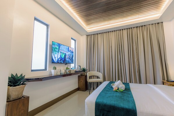 A hotel room with a bed, a TV on the wall, a window, and curtains. - LOBOC RIVERSIDE INN and RESTAURANT (Loboc)