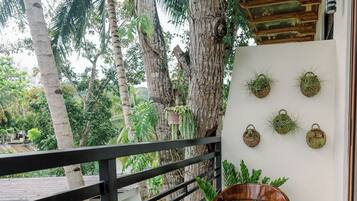 A balcony with a wooden chair, a small table with a potted plant, and a tiled floor with a geometric pattern.