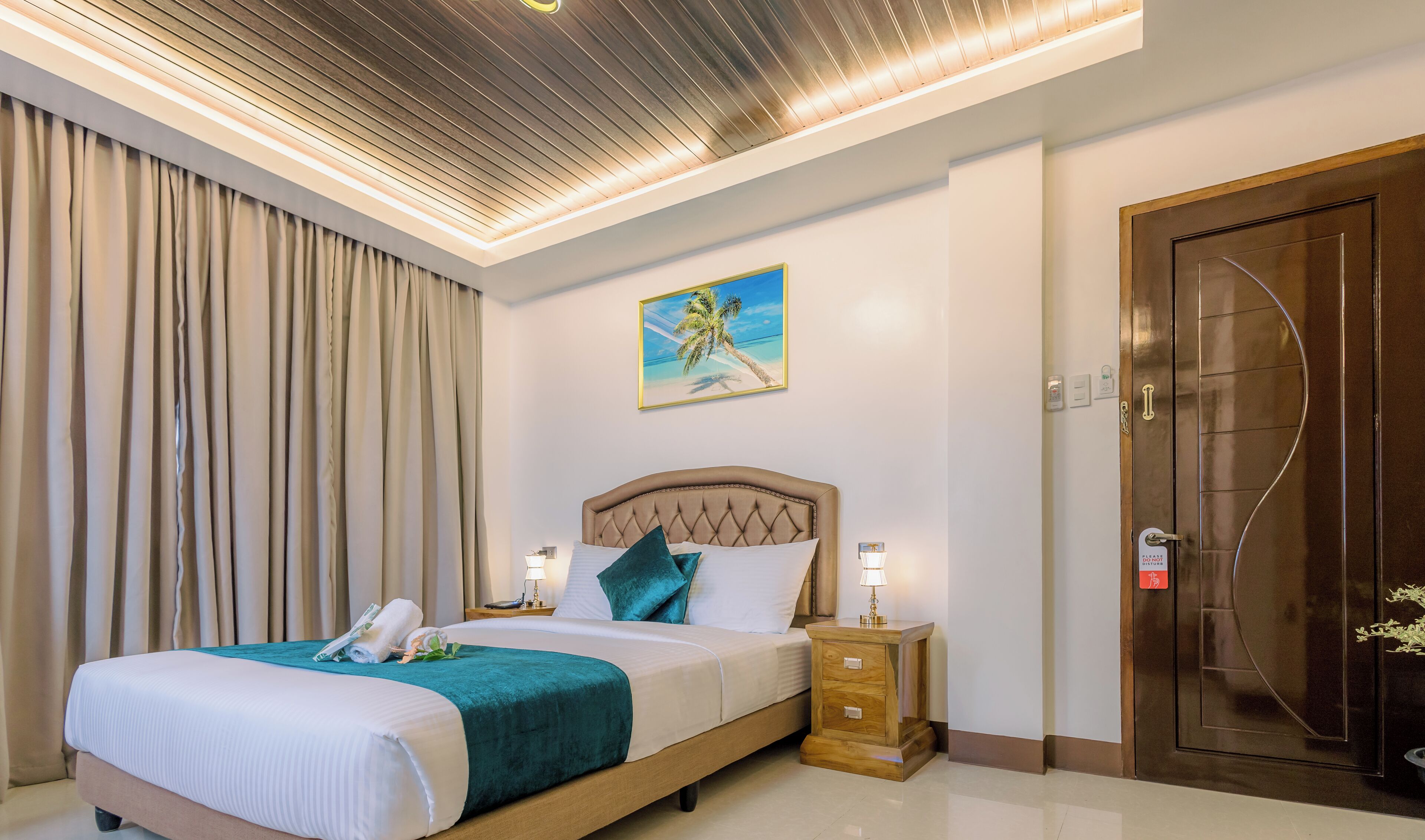 Une chambre d’hôtel avec un lit, une table de chevet, un tableau accroché au mur et une porte en bois.
