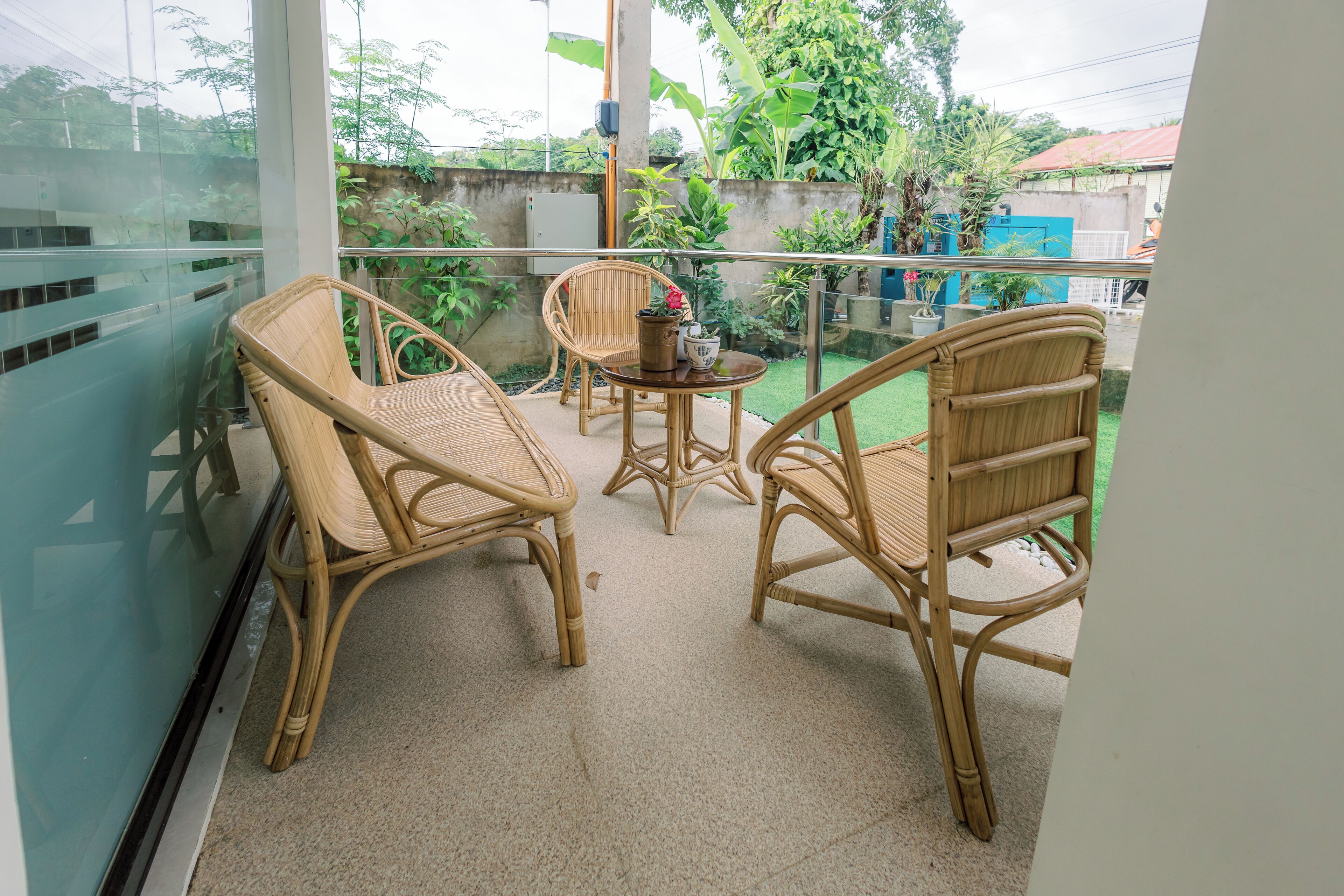 A balcony with wicker furniture, a small table, and potted plants.