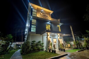 Um hotel moderno com uma placa de destaque, um jardim bem cuidado e um caminho claro para a entrada.