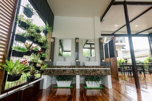 Casa de banho moderna com um espelho grande, duas pias e uma variedade de plantas em vasos.