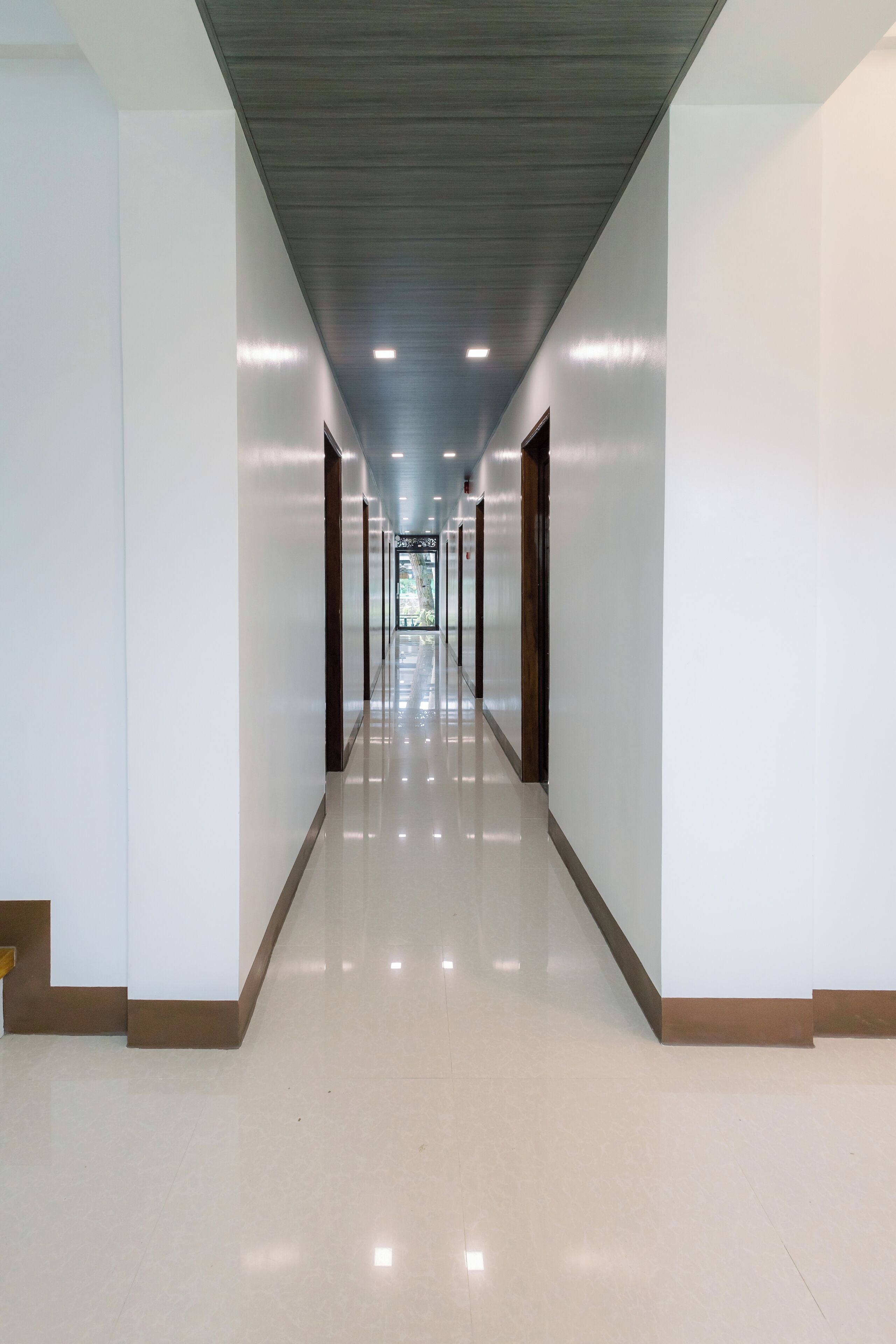 A long, well-lit hallway with a shiny floor, leading to a door at the end.