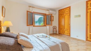 Une chambre à coucher avec un lit, une chaise, une fenêtre avec des rideaux et une armoire.