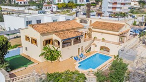 Une maison à deux étages avec une piscine, un patio couvert et un jardin.