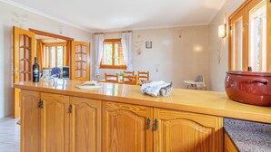 Une cuisine avec des meubles en bois, un grand îlot central et une casserole rouge.