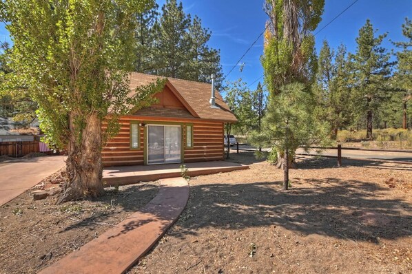 A small log cabin with a wooden exterior, a large window, and a door. - Brother Bear Cabin (Big Bear City)