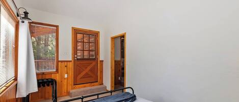 A bedroom with a bed, a wooden door, a window with blinds, and a ceiling fan.