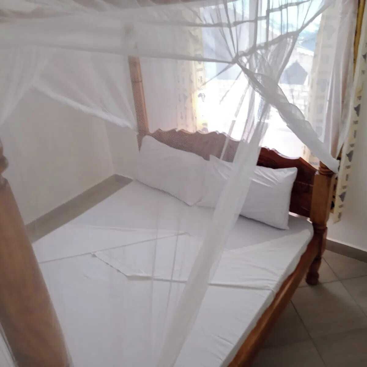 A bed with a canopy, white bedding, and a wooden headboard.