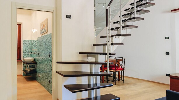 Een modern interieur met een spiltrap, een houten vloer en een eetgedeelte met tafel en stoelen.
