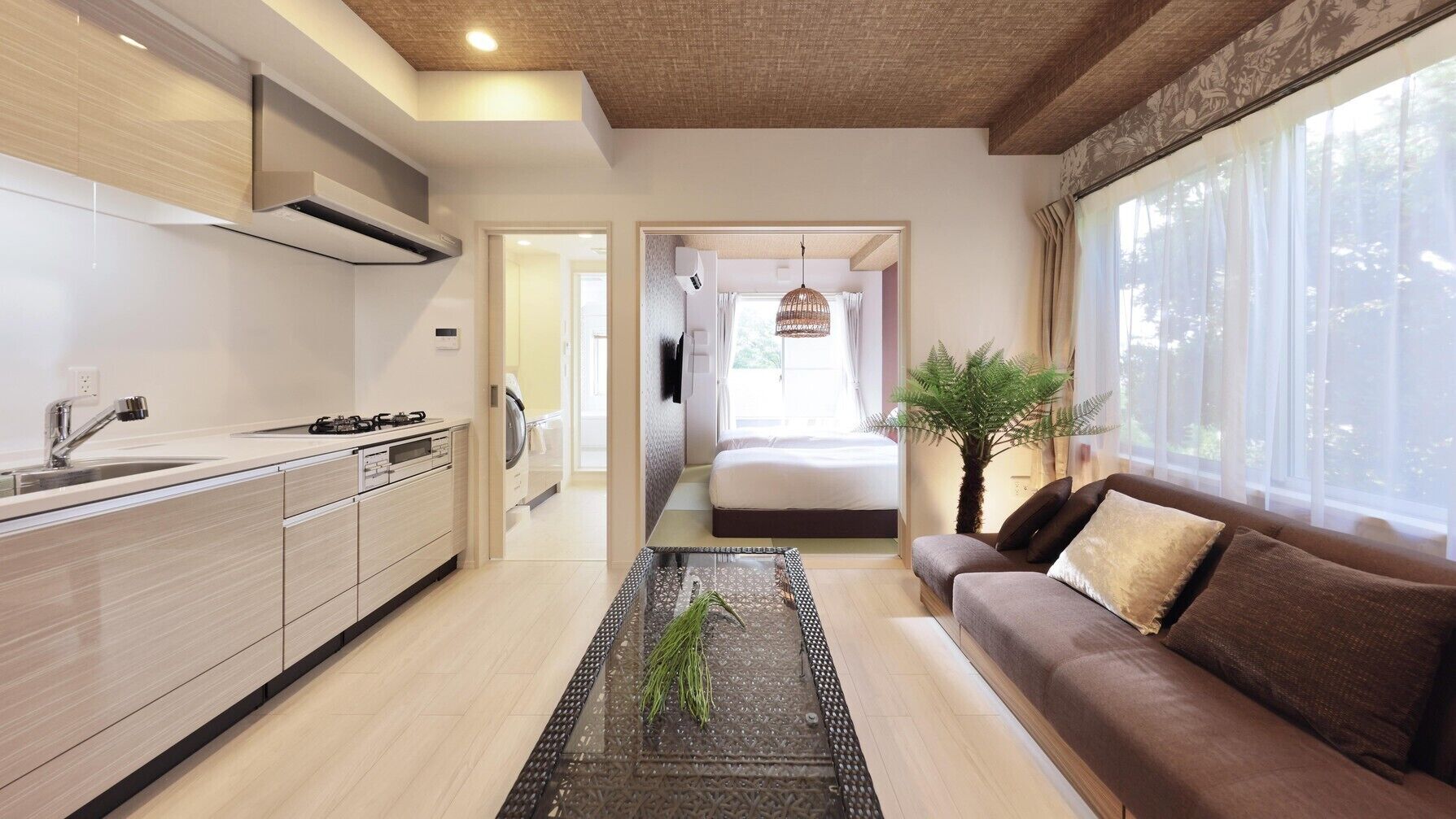 Une cuisine moderne avec un îlot central, un coin repas avec un canapé et une chambre avec un lit et une fenêtre.