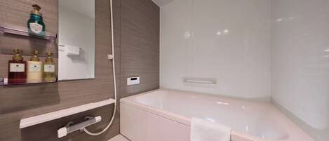 A modern bathroom with a large bathtub, a shower, and a vanity with a mirror and shelves holding toiletries.